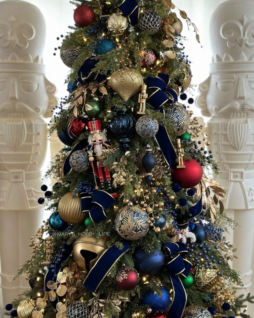 A Christmas tree decorated with blue and gold ornaments, navy velvet ribbons, and small nutcracker figurines.
