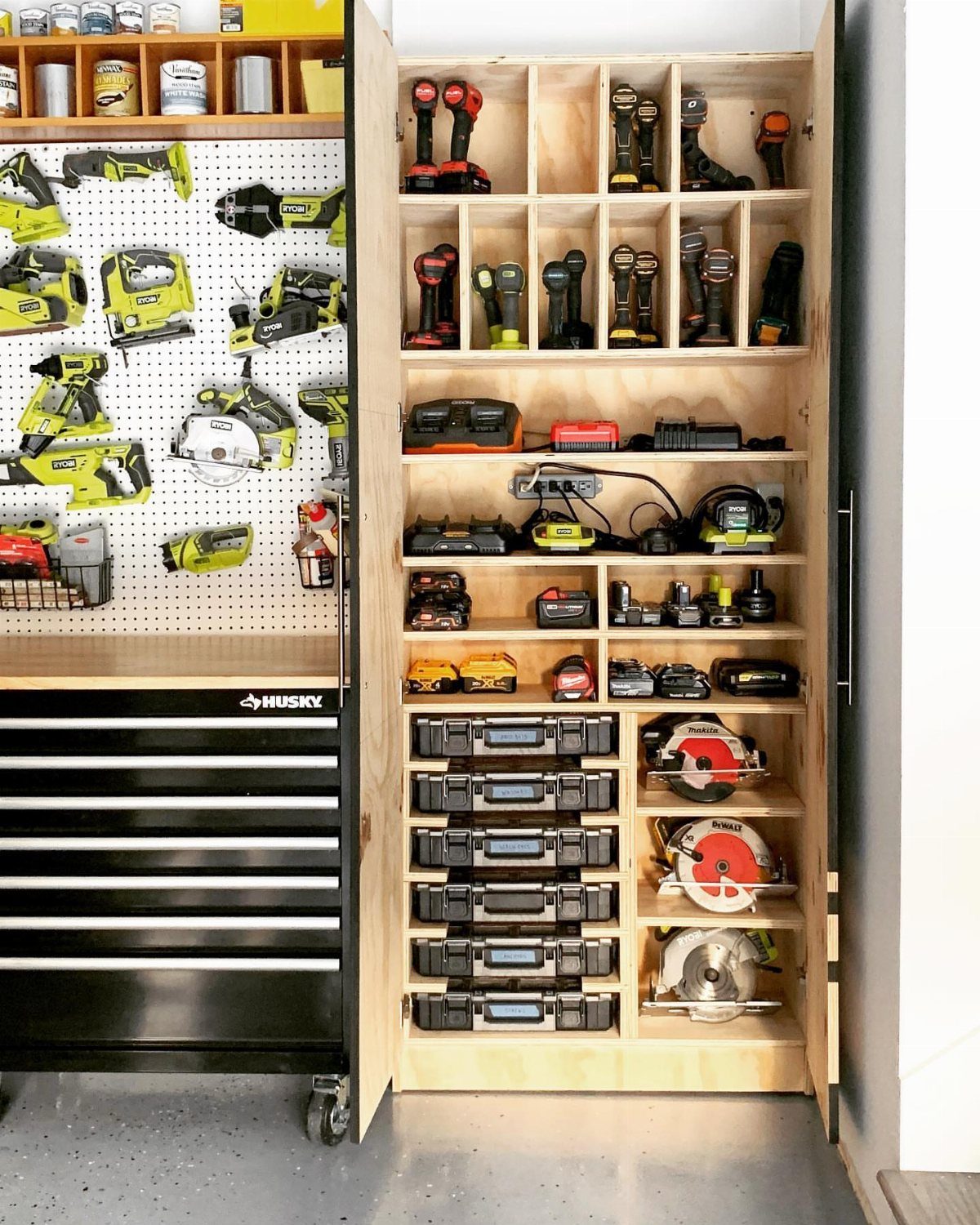 Wooden tool organizer cabinet and black tool chest filled with various power tools and accessories.