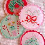 Four scalloped circular ornaments featuring hand-painted pastel holiday designs like a wreath, nutcracker, and Christmas tree.